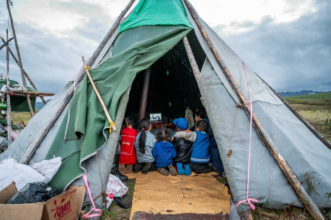Children gather inside a traditional tent, known as an ortz, in the Siberian taiga of northern Mongolia, watching a documentary about a Norwegian reindeer herder who was visiting the taiga to meet and learn about the lifestyle of the region's nomadic Dukha reindeer herders. Despite its remote and isolated location deep in the forest - accessible only by horseback or reindeer - modern technology such as solar panels, car batteries, and occasional wifi connection, allows these families to stay connected with the outside world.