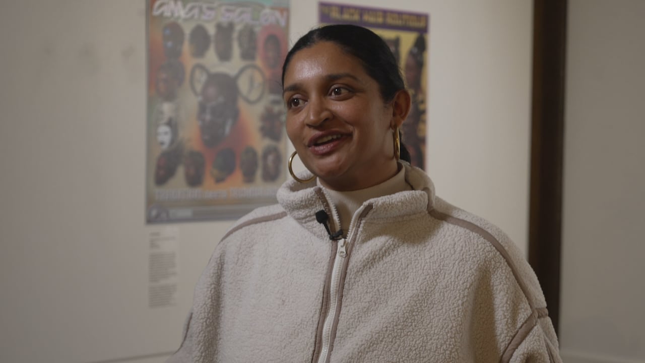 Artist, Rajni Perera stands in a gallery and speaks to a reporter.