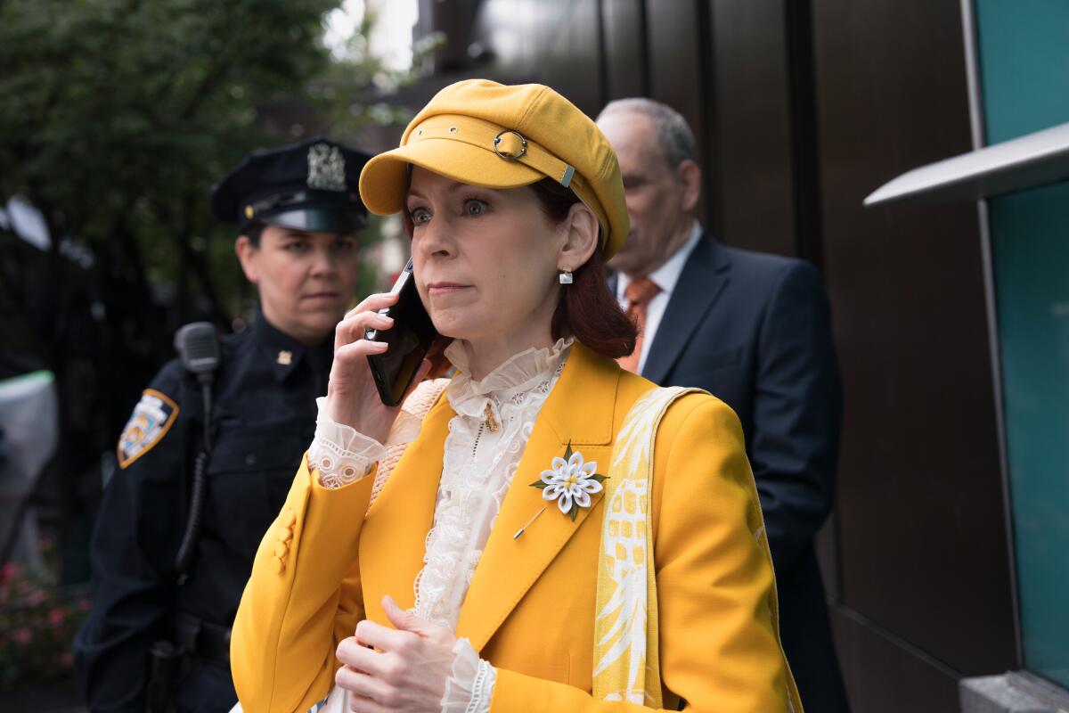 A woman in a yellow suit talks on a cell phone.