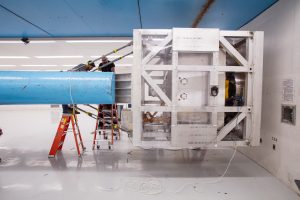 Toby Gomez, left, and Jason King work on sensor connections while the VIPER rover is suspended in a cage at the end of the Superfuge arm at Sandia National Laboratories. (Photo by Dave Linneman) Click on the thumbnail for a high-resolution image. 