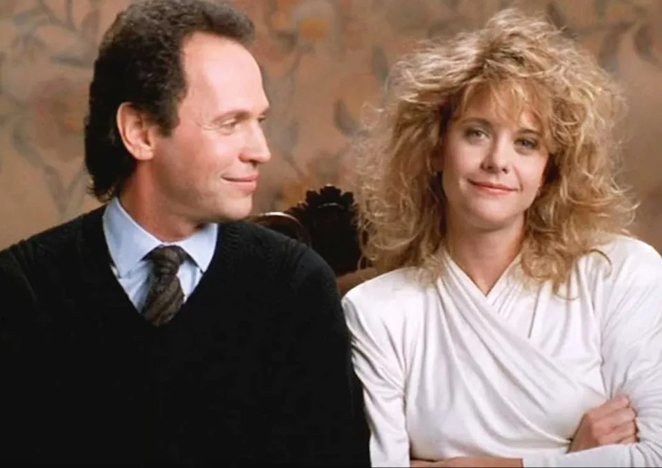 Two people sit together, both looking content. The person on the left wears a sweater, and the person on the right wears a wrap-style top