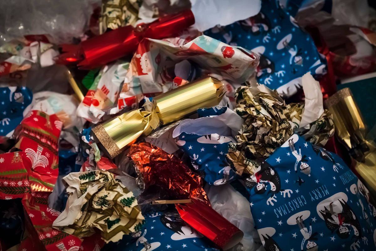 An assortment of assorted gift boxes and wrapping papers, some adorned with festive ribbons and ornaments, are gathered in a haphazard pile.