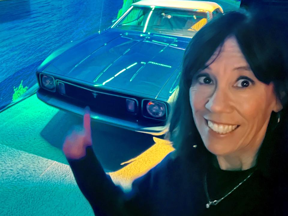 Karen Foshay, an executive producer at LA Times Studios, poses on Nov. 6 near a Mustang convertible from "The Mary Tyler Moore Show." The Mustang is part of a special exhibit open until early February in Los Angeles called "American Icon: A Mustang Immersive Experience."