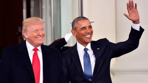 Getty Images Trump and Obama standing together wearing suits and waving