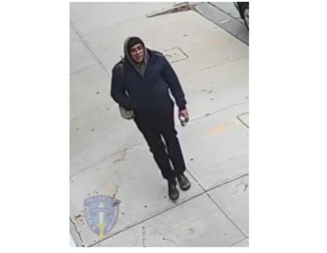 Person in dark jacket and dark pants on sidewalk