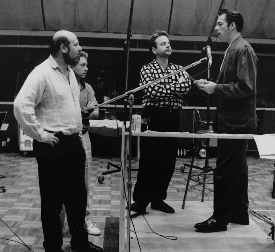 Four men in a recording studio with musical instruments and audio equipment, collaborating on the soundtrack for a film
