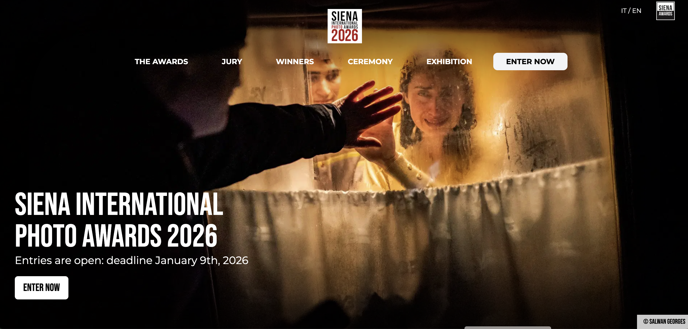The website for the Siena International Photo Awards 2026, featuring a dramatic photograph of a man reaching toward a woman's face through a misty barrier and text indicating the entry deadline is January 9th, 2026.