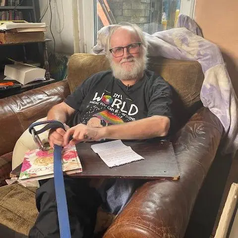 Jeremy Gavins sits on his arm chair at home holding a letter on his lap.