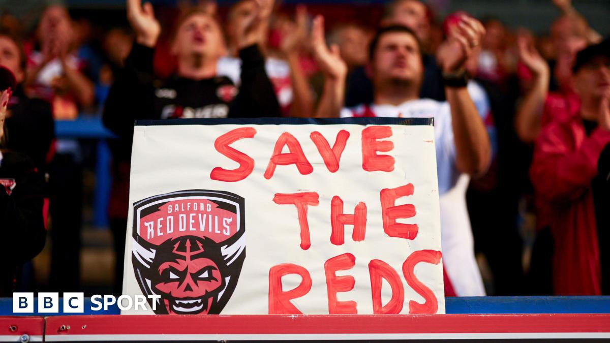 A placard with "Save The Reds" and Salford Red Devils' club crest is displayed by their fans at a recent Super League game