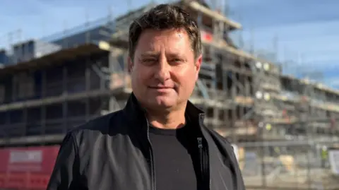 BBC George Clarke in front of the HICSA. The building has scaffolding around it and is located just a stone's throw from the Sheepfolds leisure complex.