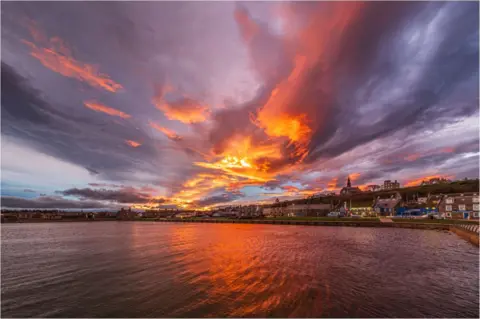 Alan Butterfield A harbour with a red, orange and purple sky