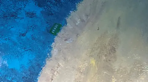 On the edge of the painting of the moon is a green bus.