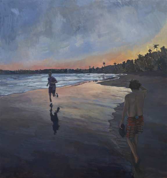 Two people walking on a beach at sunset with reflections on the wet sand and silhouettes of palm trees in the background.