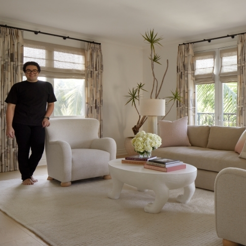 Image of a man in all black standing in a soft minimalist living room.