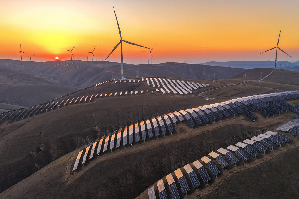 The sun sets behind wind turbines and rows of solar panels at a renewable energy farm in Qingyang, China. Credit: Chen Kun/VCG via Getty Images