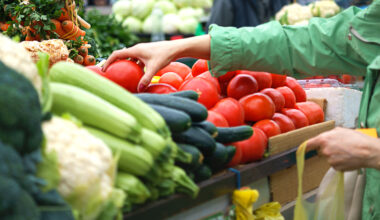 A person picking up fresh vegetables in an open market.