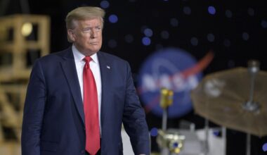 President Donald Trump in a red tie surrounded by NASA hardware