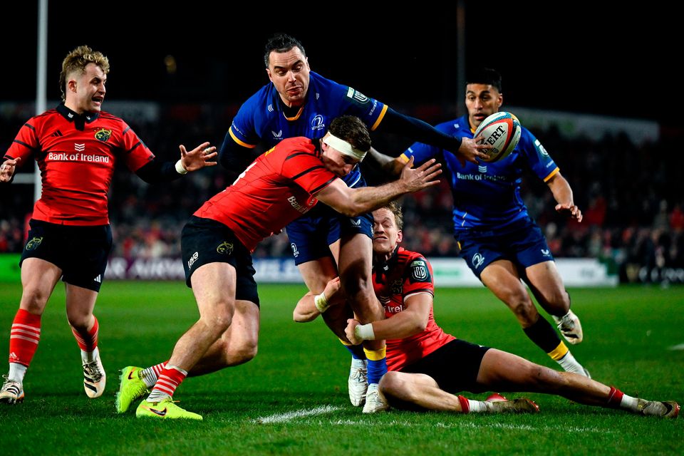 James Lowe of Leinster offloads to teammate Rieko Ioane, right, as he is tackled by Shane Daly, left, and Mike Haley of Munster in the URC match at Thomond Park in Limerick. Photo: Brendan Moran/Sportsfile