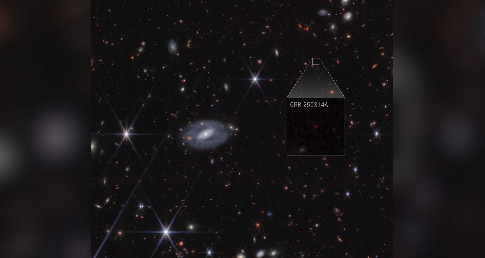 A deep space image showing various colored stars and galaxies, with a boxout showing a supernova with the label GRB 250314A, in white text