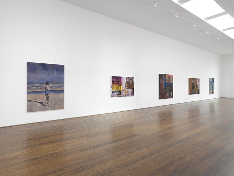 Contemporary art gallery interior with various paintings displayed on a white wall and wooden flooring.