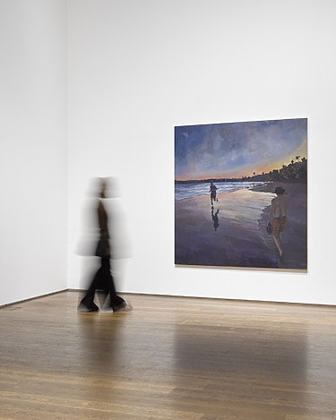 Person walking past a large painting in an art gallery, featuring a coastal scene with two figures at sunset.