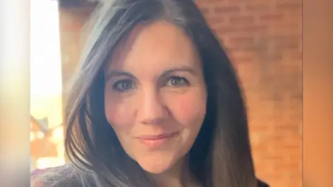 Victoria Moore Image of Victoria. She has brown hair and is stood in front of a wall. 