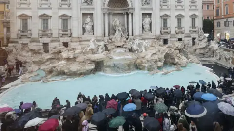 EPA-EFE/REX/Shutterstock Tourists stand and look on at the Trevi Fountain
