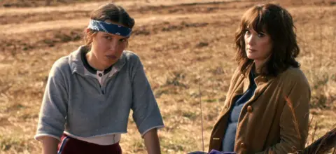 Netflix Millie Bobby Brown as Eleven and Winona Ryder as Joyce Byers in Stranger Things: Season 5