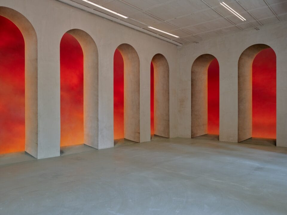 An art installation by Clementine Keith-Roach and Christopher Page of architectural arches with red, atmospheric paintings in each portal