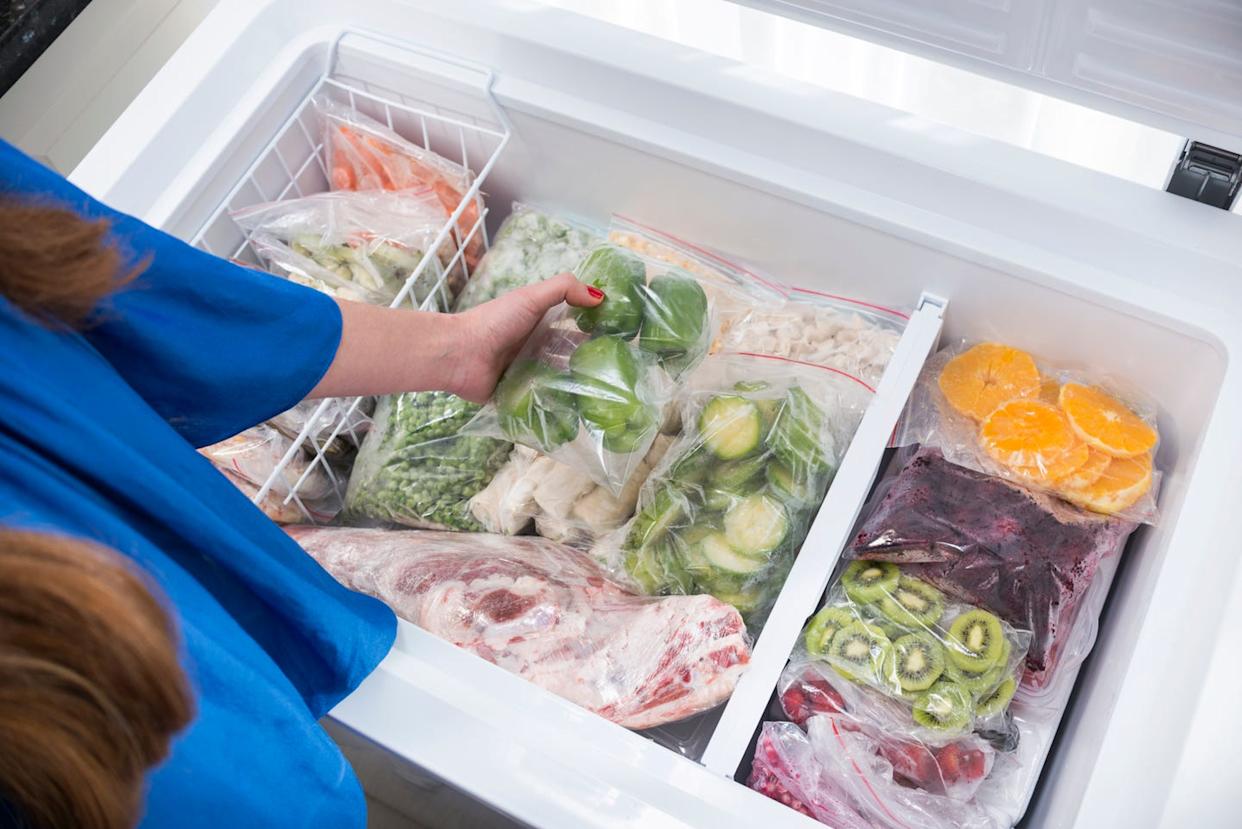 a woman putting green bell peppers into freezer