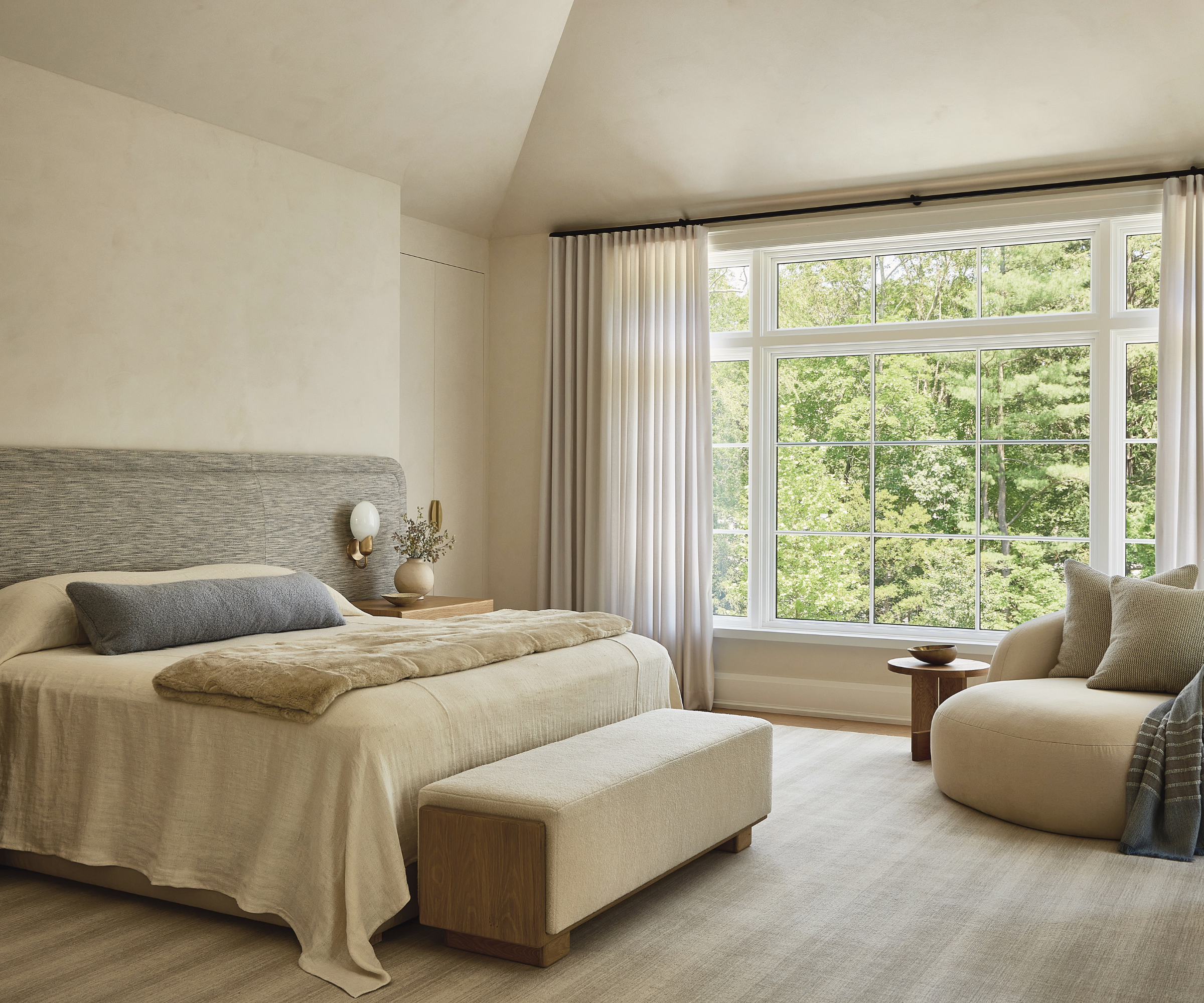 An ivory-toned primary bedroom with vaulted ceilings.