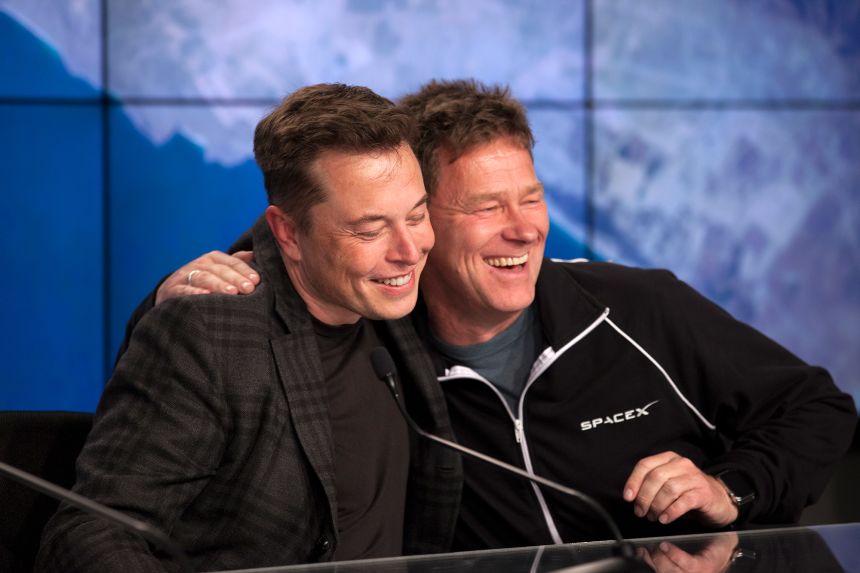 Elon Musk and Hans Koenigsmann embrace during a post-flight news conference following the successful launch of SpaceX's CRS-8 mission to resupply the International Space Station in 2016.