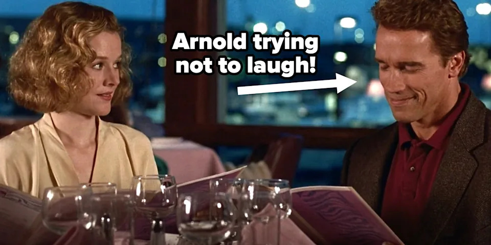 Two people at a restaurant table, holding menus and smiling. Glasses on the table. Scene from a movie