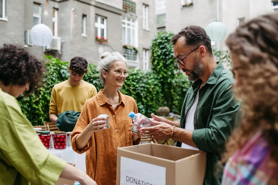 People sorting donation items outdoors, with containers on tables