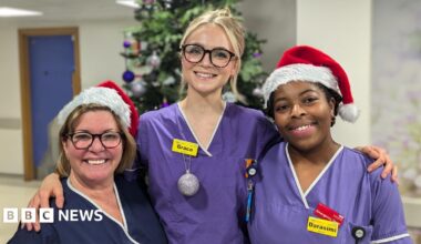 Three women in medical scrub. There is a Christmas tree behind them.