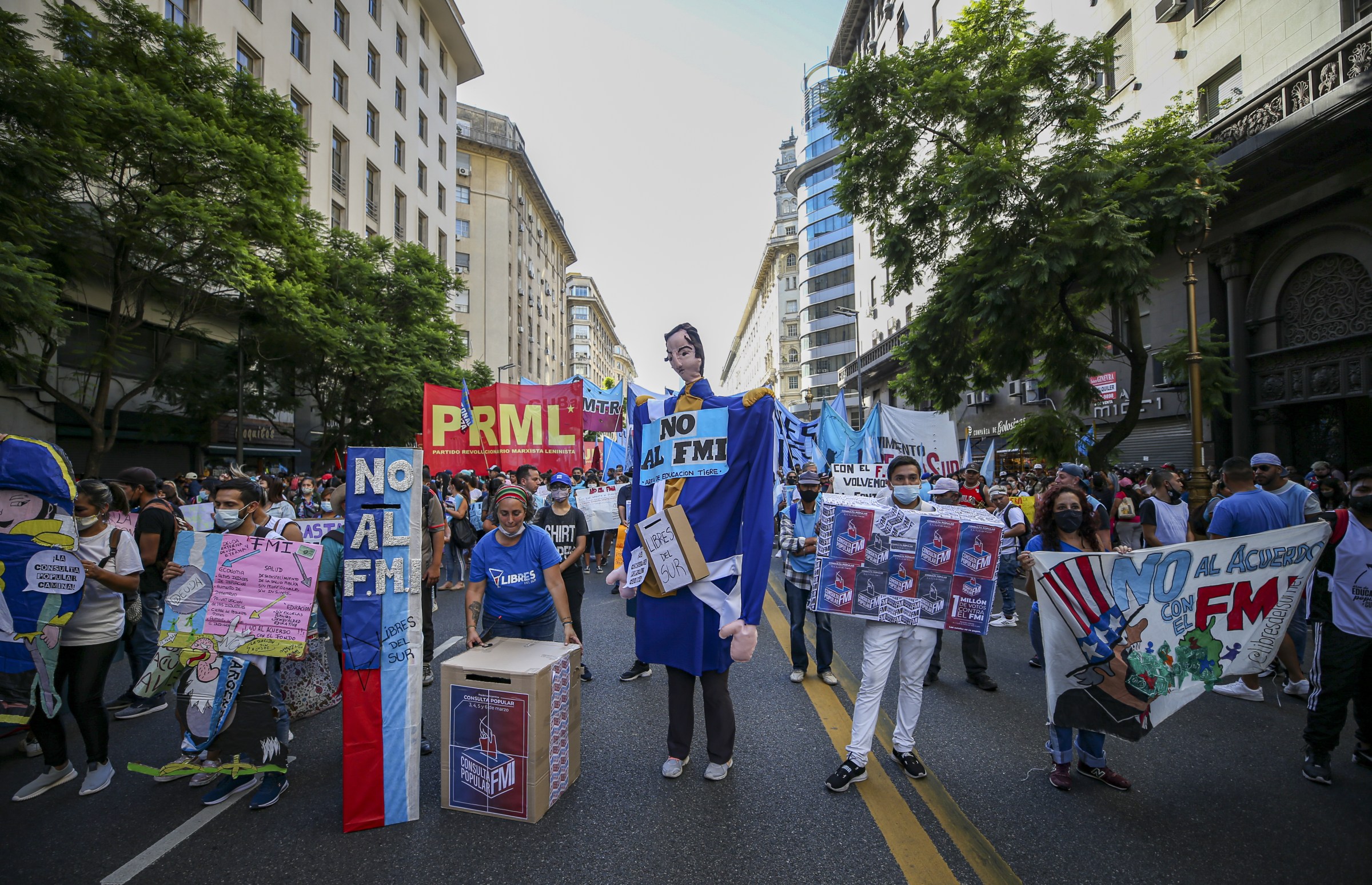 A group of protesters in Argentina hold colorful signs denouncing the IMF and austerity.