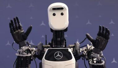 Apollo humanoid robot prototype by Apptronik Inc. raises its hands in front of a backdrop with Mercedes-Benz logos.