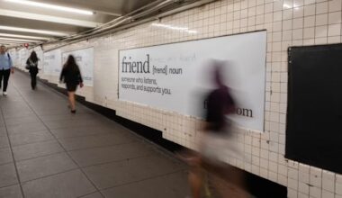 Advertising posters for the “Friend” AI device line a subway corridor, with visible graffiti reading “AI is not your friend.”