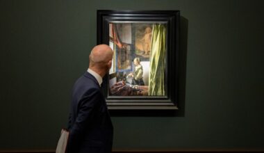 A man in a suit looks at Johannes Vermeer’s painting "Girl Reading a Letter at an Open Window" displayed in a gallery.