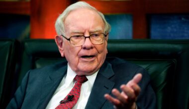 Warren Buffett speaks while seated, gesturing with his hand during an interview.