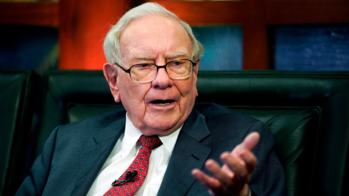 Warren Buffett speaks while seated, gesturing with his hand during an interview.