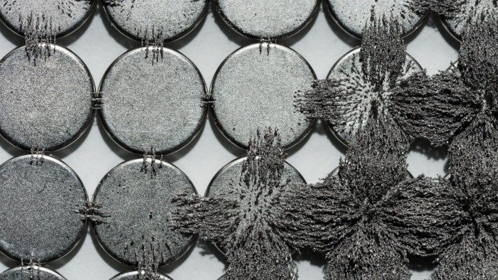 Iron filings form interlocking star-shaped patterns around circular magnets, revealing the magnetic flux lines.