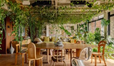 An apartment interior designed by Guto Requena with an eclectic variety of contemporary furnishings and houseplants draping from rafters in the ceiling