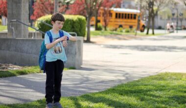 A child in front of a school looking at his smartwatch