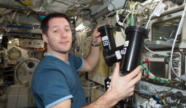 European Space Agency astronaut Thomas Pesquet works inside the International Space Station, . He is holding two cylindrical black experiment containers to deactivate and stow the Protein Crystal Growth-5 hardware. The background is filled withIn the background, cables, silver knobs, instruments, and research equipment are visible.