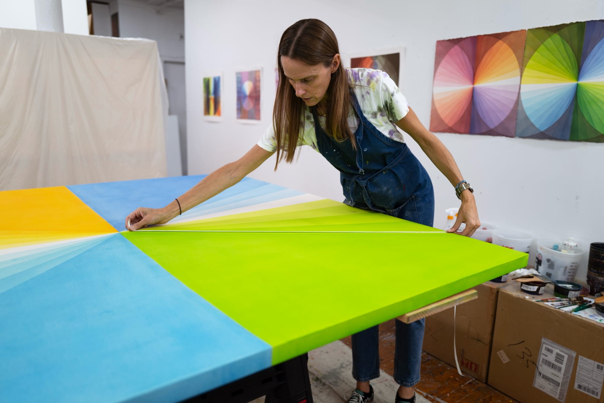the artist measures part of a canvas in her studio