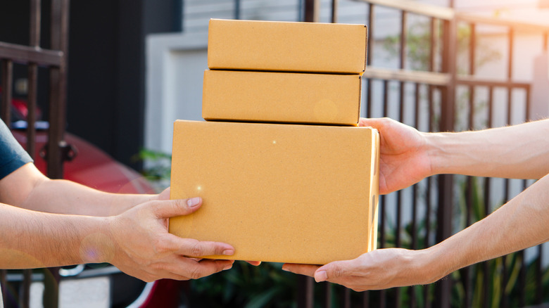 One individual handing three packages to another individual,