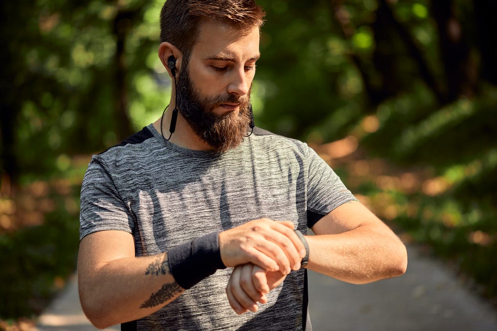 Portrait of sporty man with earphones in forest checking his smartwatch portrait of sporty man with earphones in forest checking his smartwatch