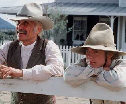 Robert Duvall and Ricky Schroder leaning against a fence in 1989's Lonesome Dove.