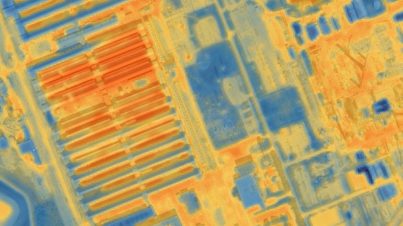 An orange, yellow, and blue heat image showing rows of orange heated architecture in the middle of an urbanized area.